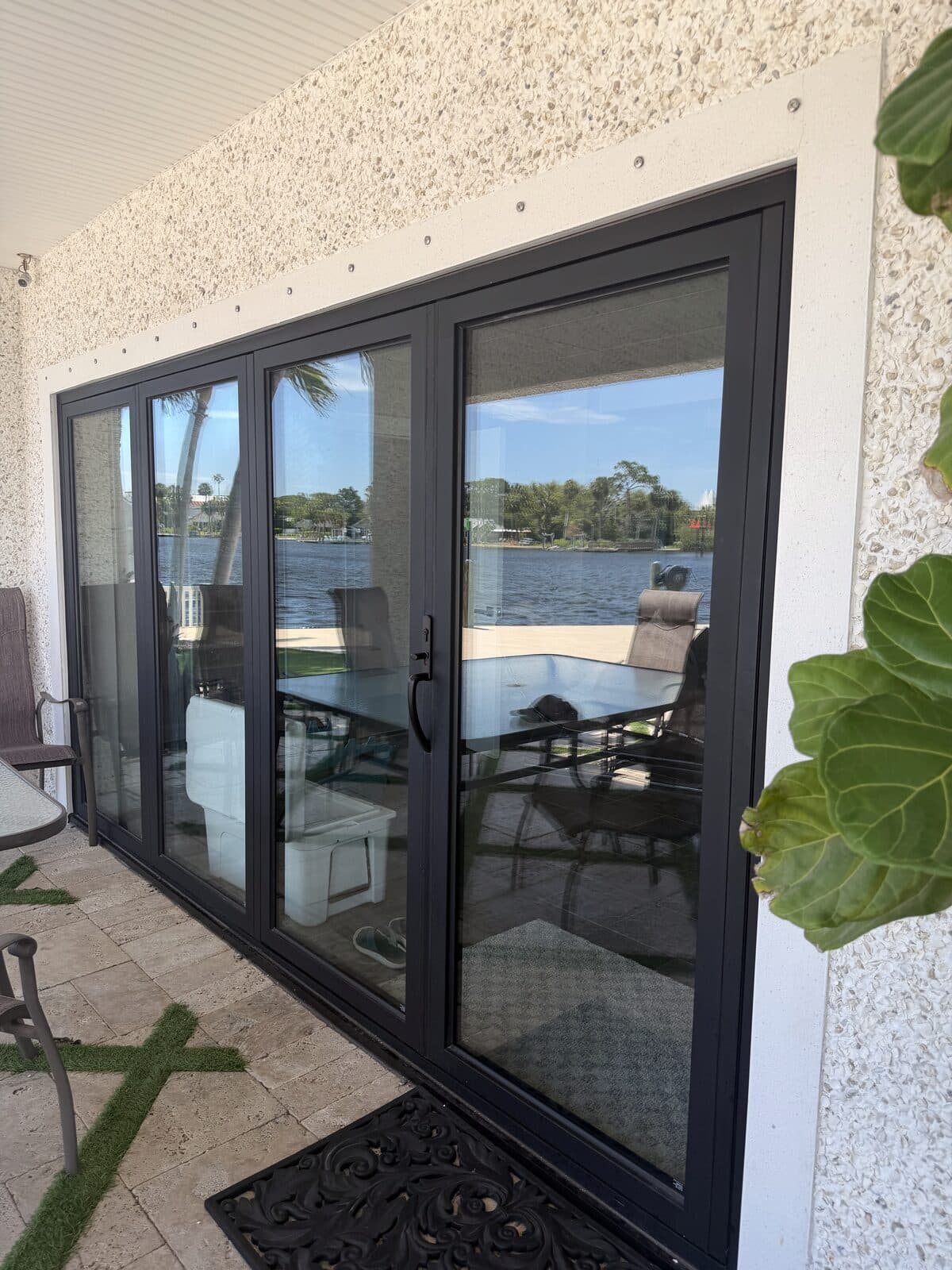 Four-panel sliding glass door opening to a waterfront patio