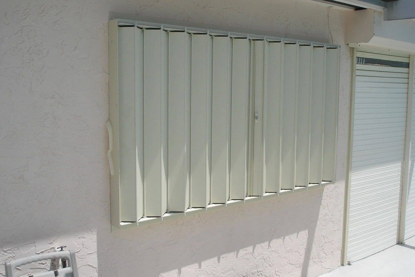 White accordion hurricane shutters protecting a home's windows