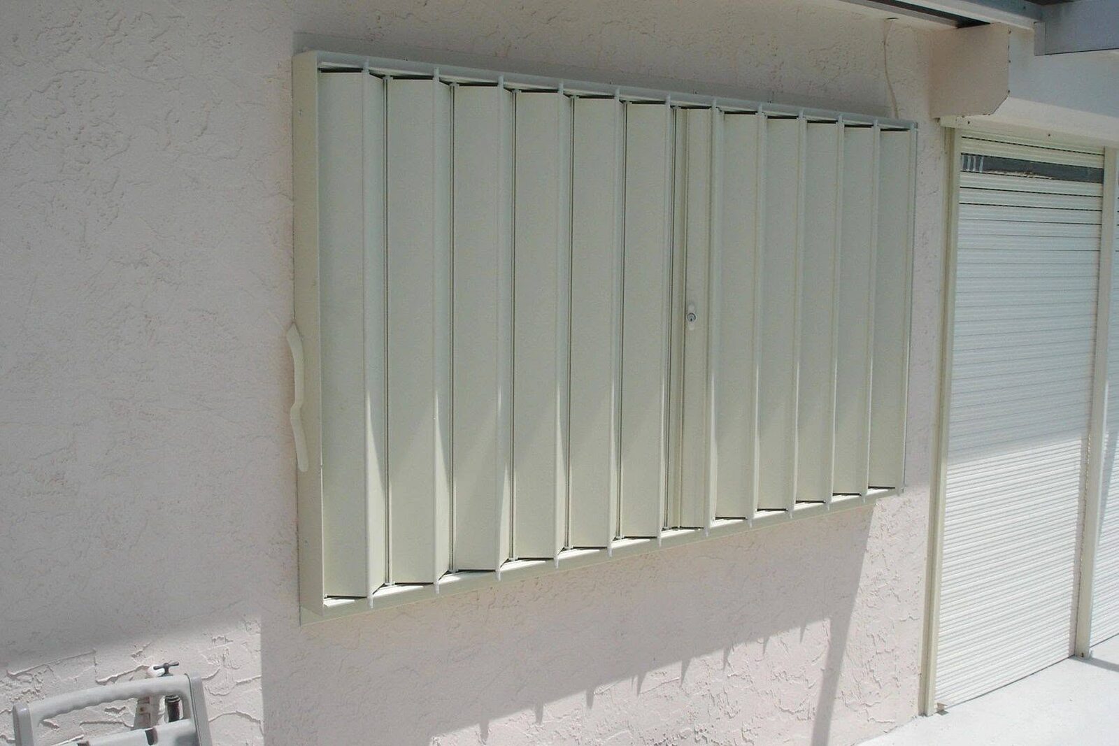 White accordion hurricane shutters protecting a window